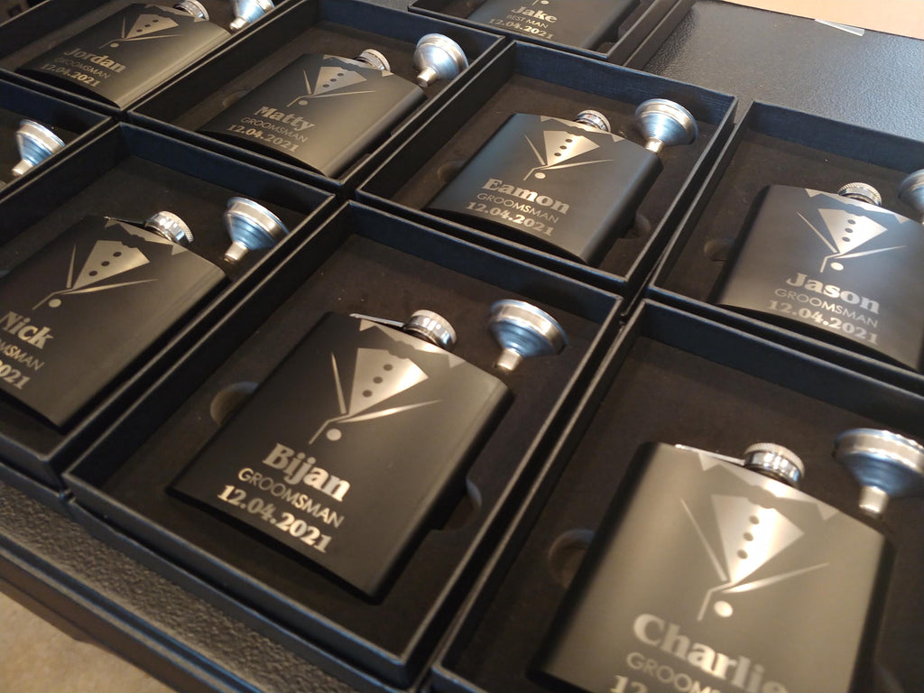 Custom engraved black groomsman flasks with tuxedo design and names in gift boxes