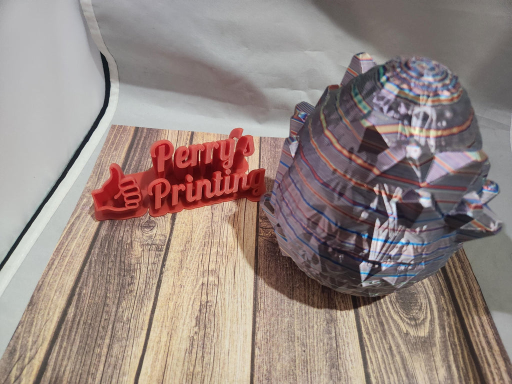 Colorful 3D printed geometric shape and red Perry's Printing sign on wood backdrop