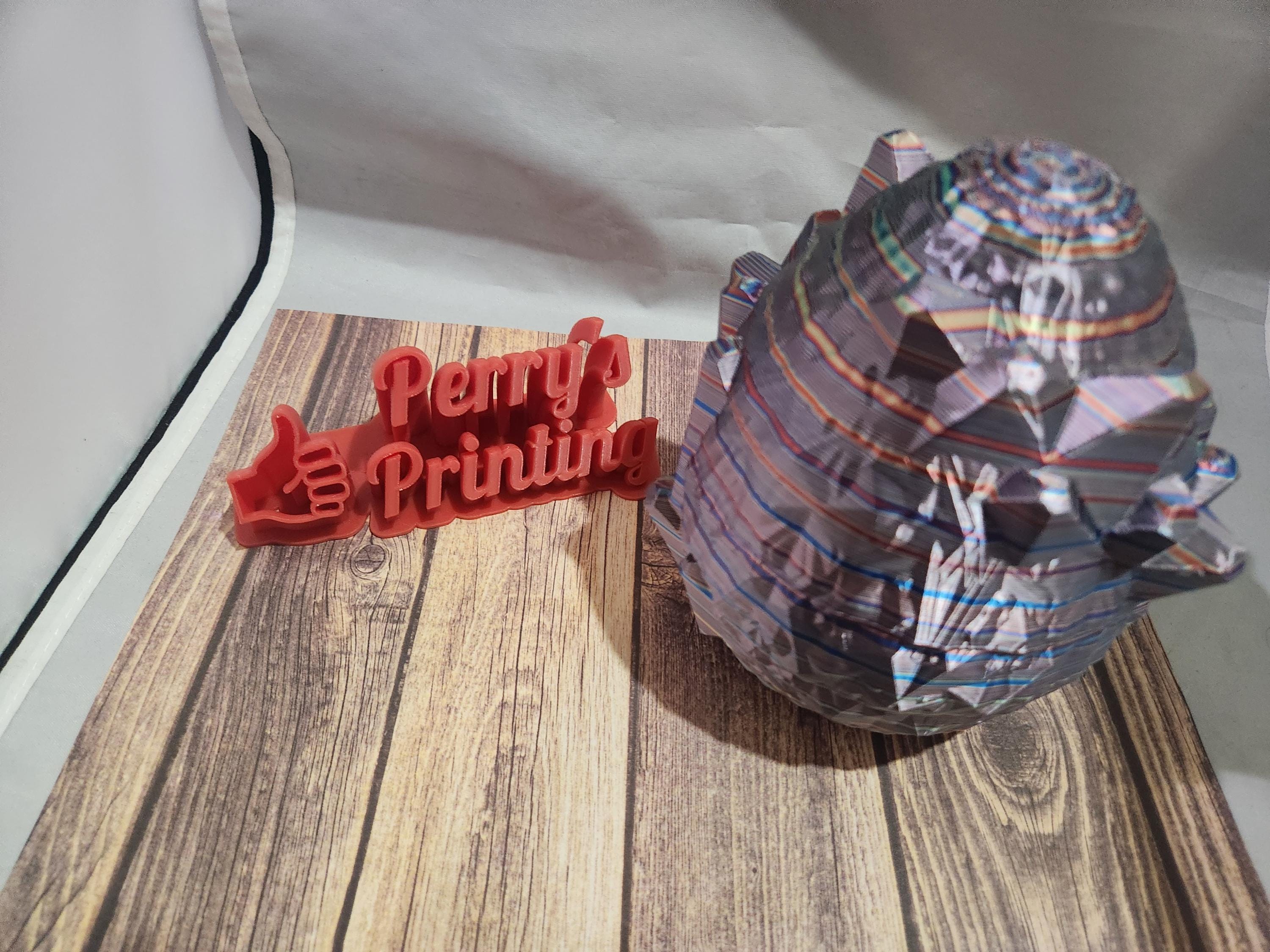 Colorful 3D printed geometric shape and red Perry's Printing sign on wood backdrop