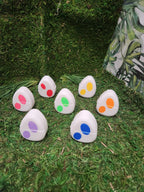 Colorful 3D printed egg-shaped objects with dot patterns on artificial grass background