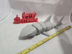 3D printed articulated shark figurine beside measuring tape and red thumbs up sign