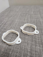 Pair of white 3D printed mounting brackets on a grey fabric surface