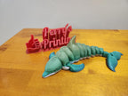 3D printed flexible dolphin figurine and red thumbs-up sign on a wooden table