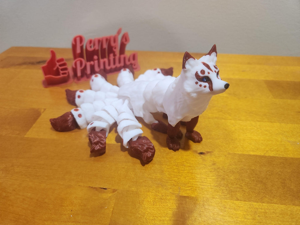 3D printed nine-tailed fox figurine with white body and brown accents on wooden surface