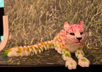 Colorful 3D printed articulated leopard figurine with green, yellow, and pink spots on grass