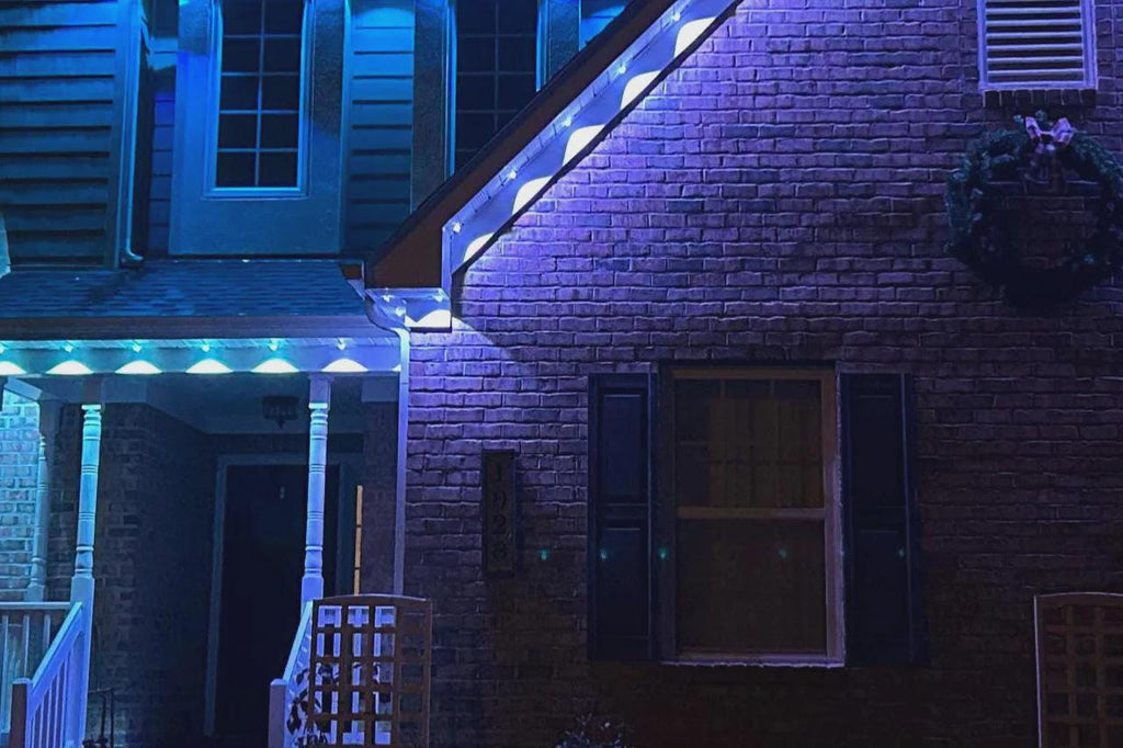 House exterior with blue LED accent lighting on brick walls and porch at night