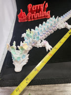 3D printed pastel flower dragon figurine measured with tape on black background