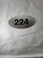 Brushed metal oval door sign with black number 224 on a white background