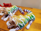 Colorful 3D printed flexible cat figure with striped pattern on wood surface