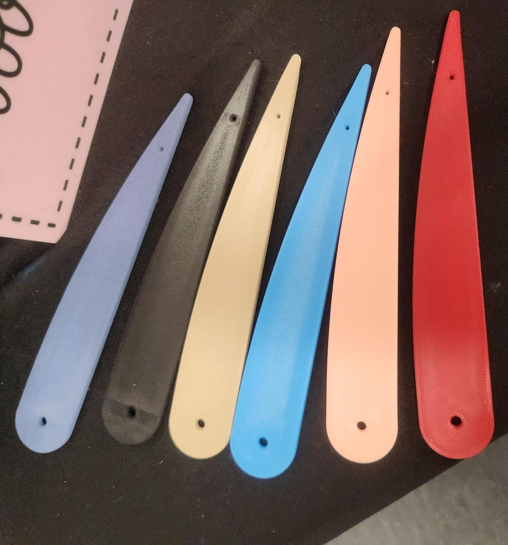 Assorted 3D printed plastic tools in various colors on a black surface