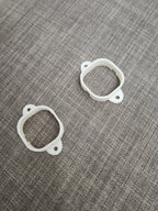 Two white 3D printed mounting brackets on a gray textured fabric background