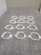 Set of twelve white 3D printed plastic mounting brackets on a gray fabric surface