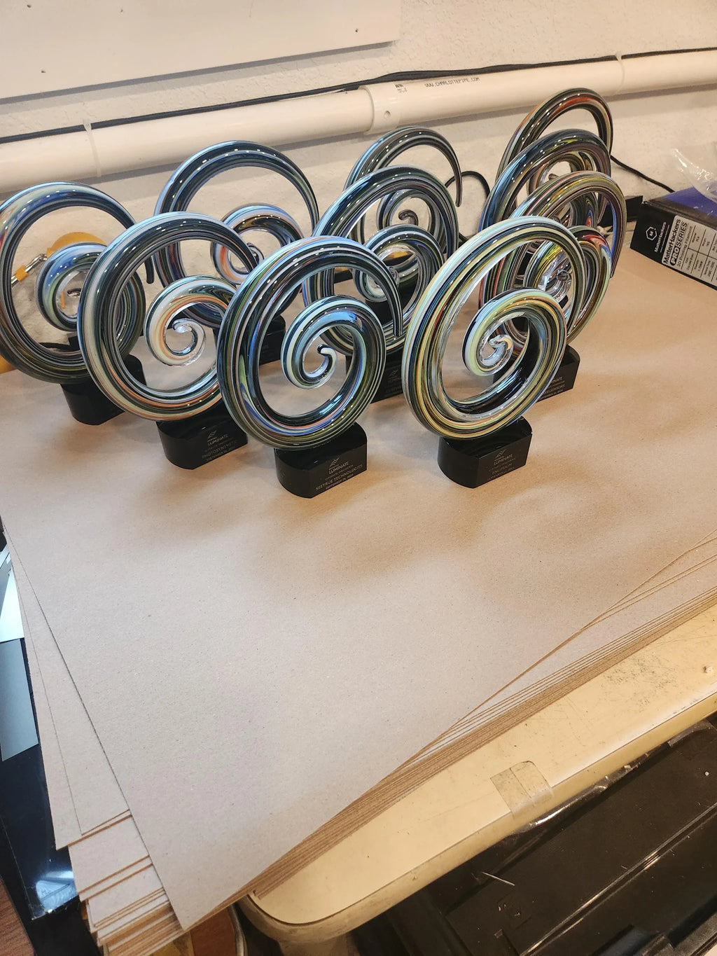Multiple glass spiral awards with black bases displayed on a table, custom engraved trophies