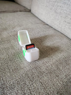 3D printed Nintendo Switch game card holder with green accents on a fabric couch