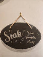 Engraved slate bathroom sign with 'Soak Your Troubles Away' and bubbles, hanging on wall