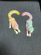 Two colorful 3D printed articulated leopard figurines with rainbow spots on a dark fabric background.