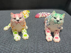 Colorful 3D printed articulated cat figurines with spotted patterns on a gray fabric surface