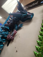 3D printed polygonal dragon wall art with blue and green geometric spikes, displayed indoors.