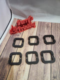 Six black 3D printed plastic mounting brackets on wood surface, red Perry's Printing sign in background