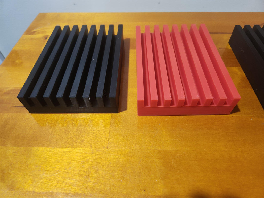 3D printed black and red slotted display stands on a wooden surface