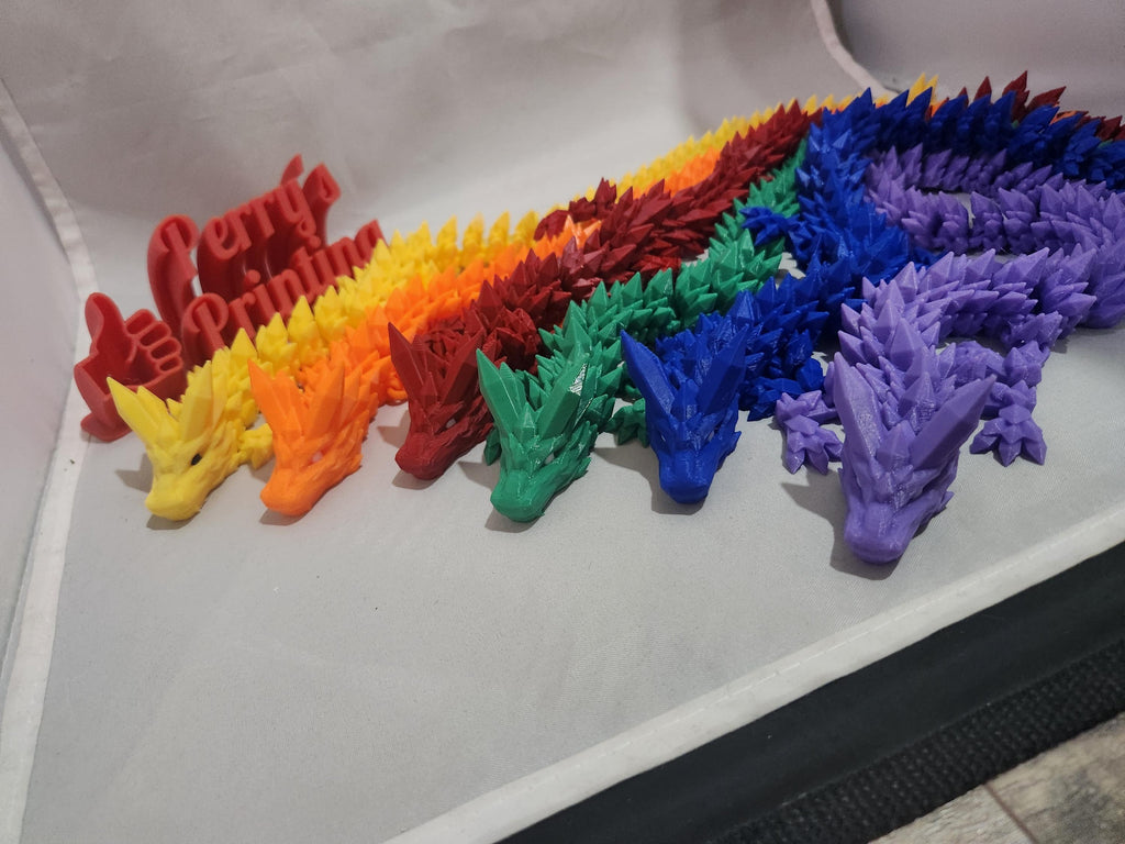 Colorful 3D printed articulated dragon toys in rainbow colors on display.