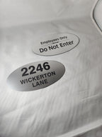 Two custom oval brushed metal signs with black text for address and employee door labels