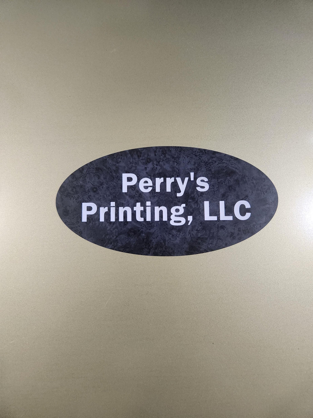 Oval black business sign with white text on a metallic gold background
