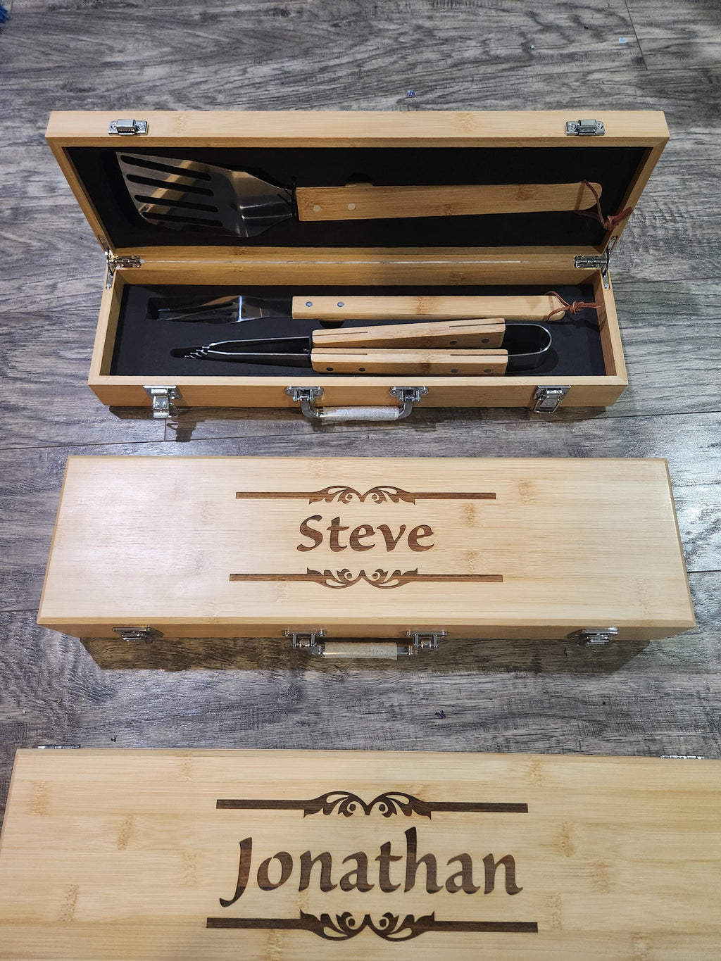 Personalized bamboo BBQ grill set with engraved names, displayed on wood floor.