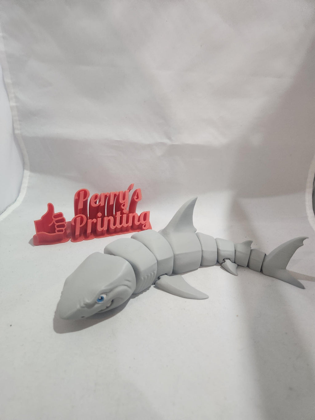 3D printed articulated shark figurine with red thumbs-up Perry's Printing sign