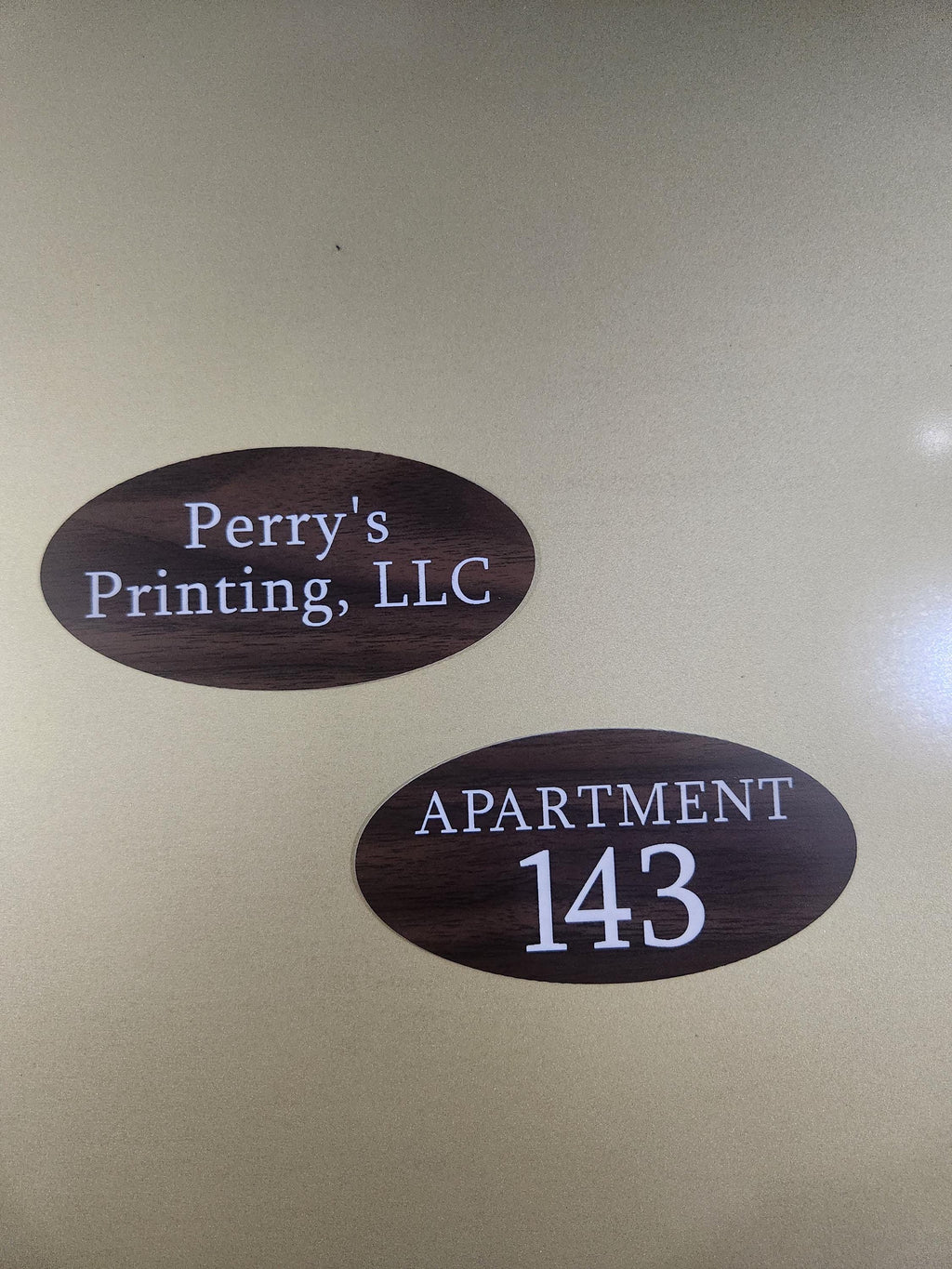 Two oval custom wood-look engraved signs, one with business name and one with apartment number.