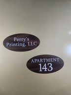 Two oval custom wood-look engraved signs, one with business name and one with apartment number.