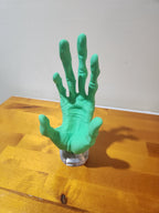 Green 3D printed hand prop with detailed texture on a wooden table