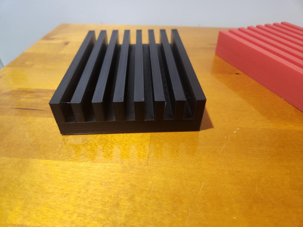 Black 3D printed grooved display stand on wooden surface with red stand in background