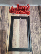 3D printed black rectangular frame with red Perry's Printing sign on a wood background