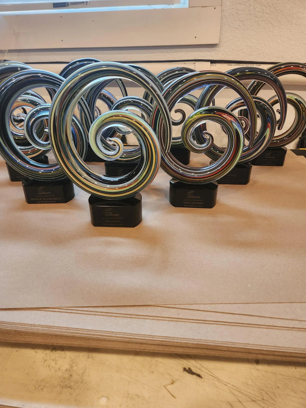 Colorful swirl glass awards with black bases displayed on a table, custom recognition trophies
