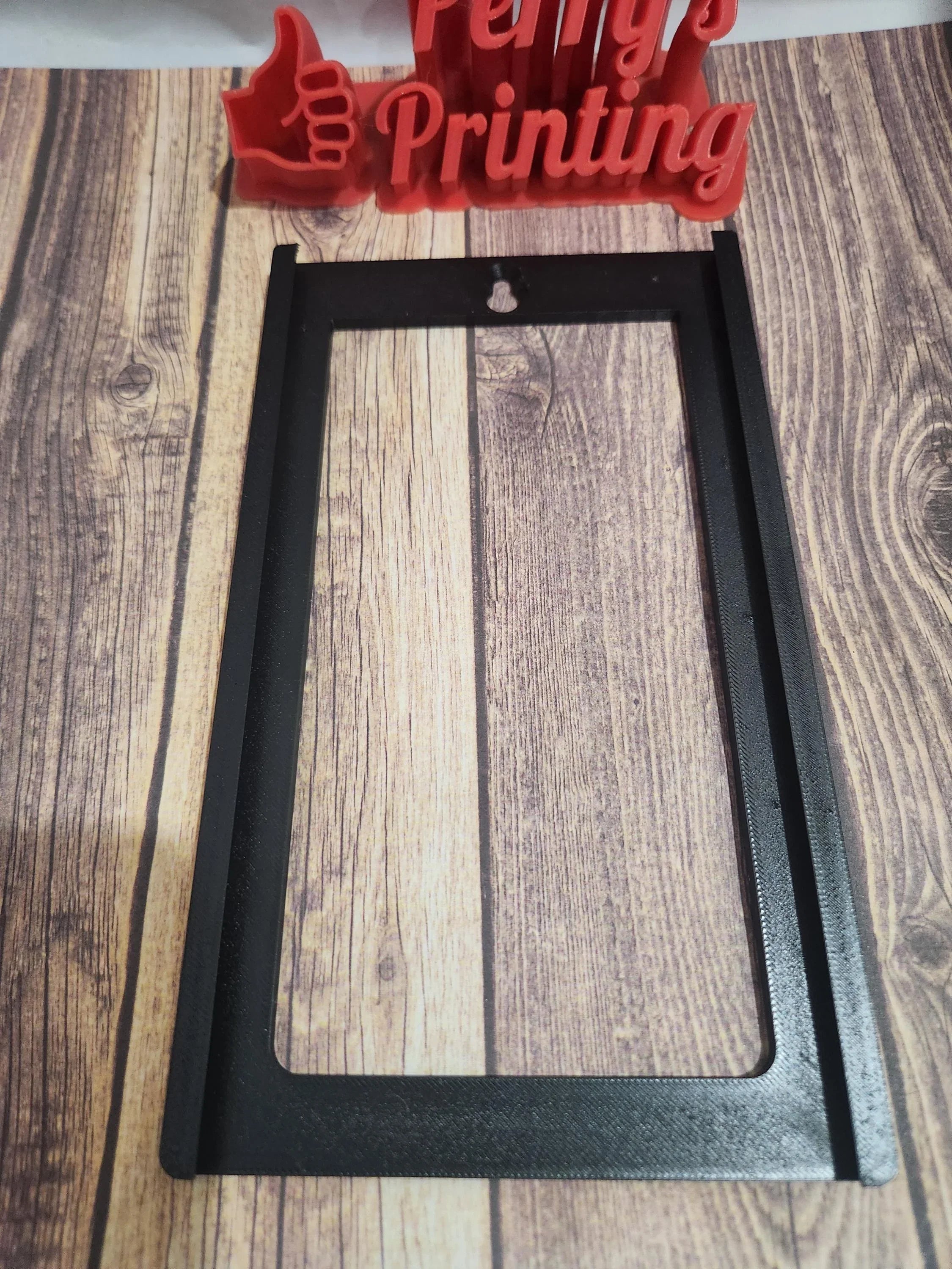 3D printed black rectangular frame for signage or engraving, displayed on wood surface