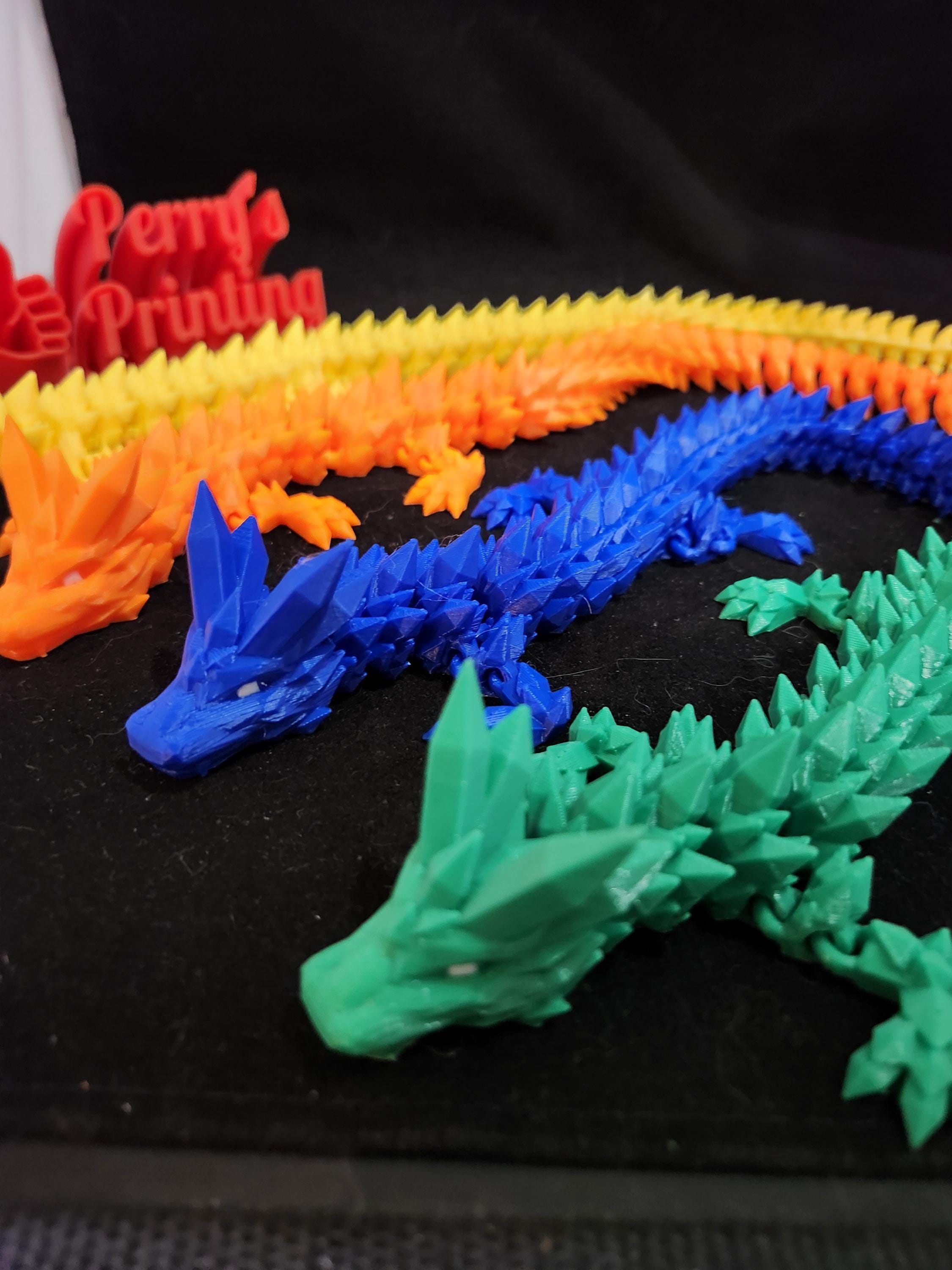 Colorful 3D printed articulated dragon figurines on black fabric background
