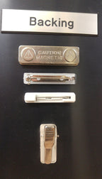 Assorted name badge backings including magnetic, pin, and clip styles on display board