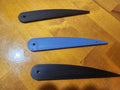 Three 3D printed plastic fan blades, two black and one blue, on a wooden surface.