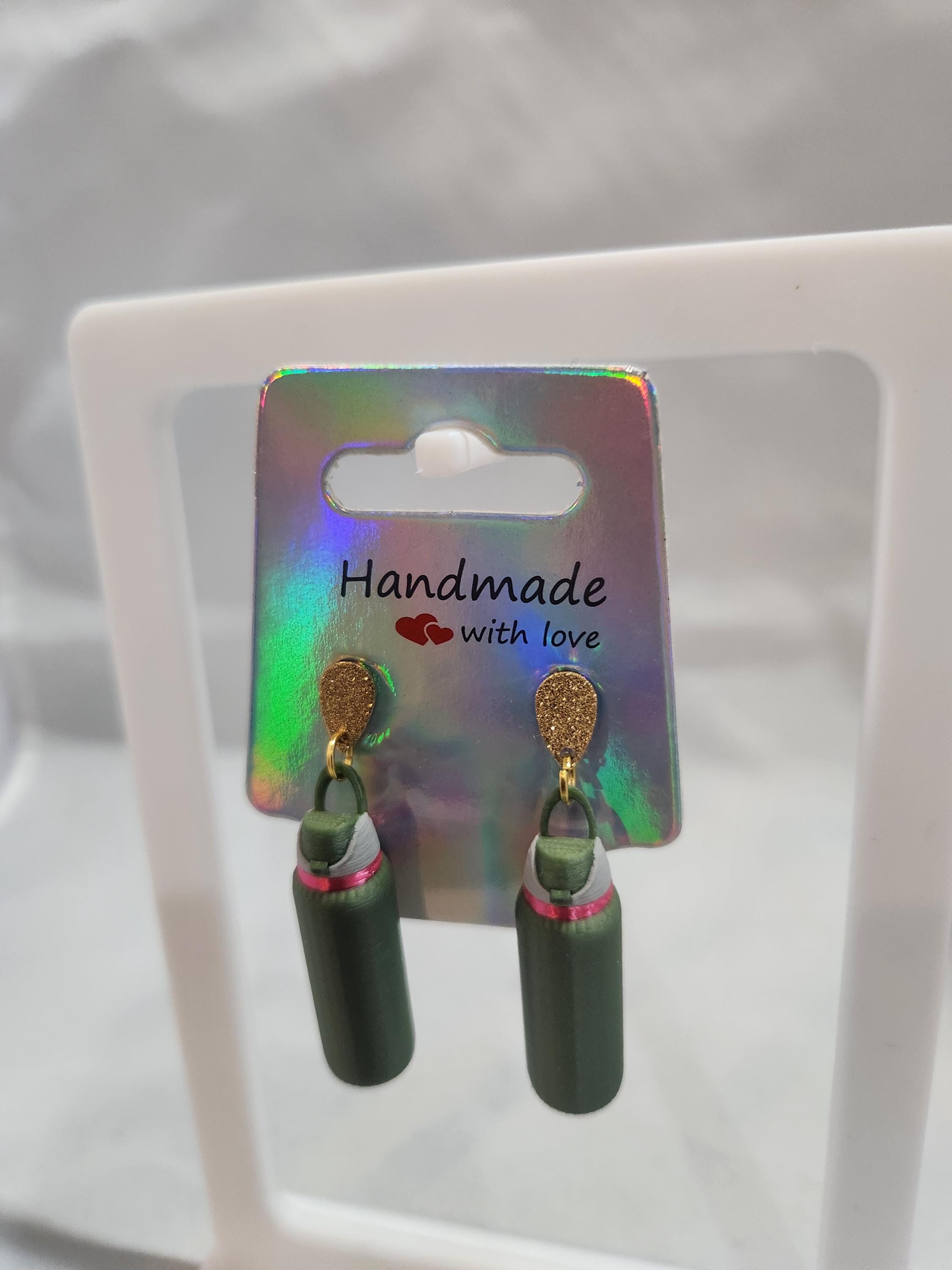Handmade 3D printed green bottle earrings with gold hooks on holographic card display
