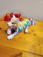 Colorful 3D printed cat figurine with stripes on wooden surface, custom signage in background