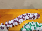3D printed segmented white and purple articulated dragon tail on wood surface