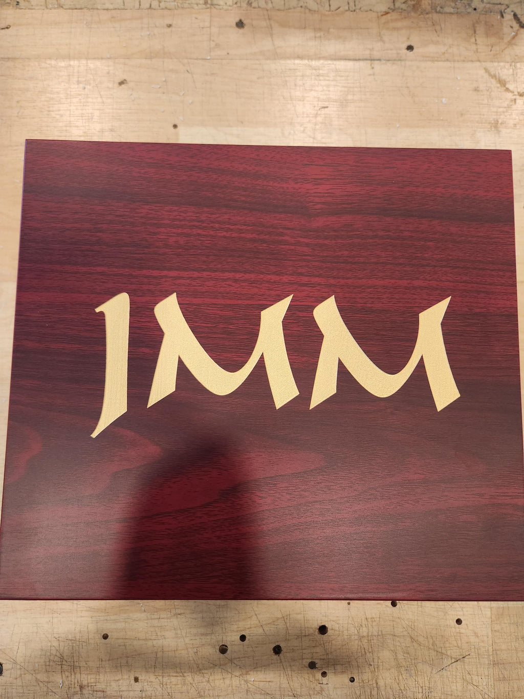 Custom laser engraved wooden plaque with gold text on a reddish wood background