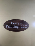 Wood-style engraved oval sign with white text reading 'Perry's Printing, LLC' on a gold background.
