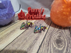 Two colorful 3D printed dragons on wood, with Perry's Printing sign in background