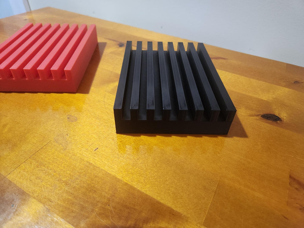Black and red 3D printed slotted blocks on a wooden table, used for organizing or display.