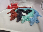 Colorful 3D printed articulated dragon models arranged on a white surface