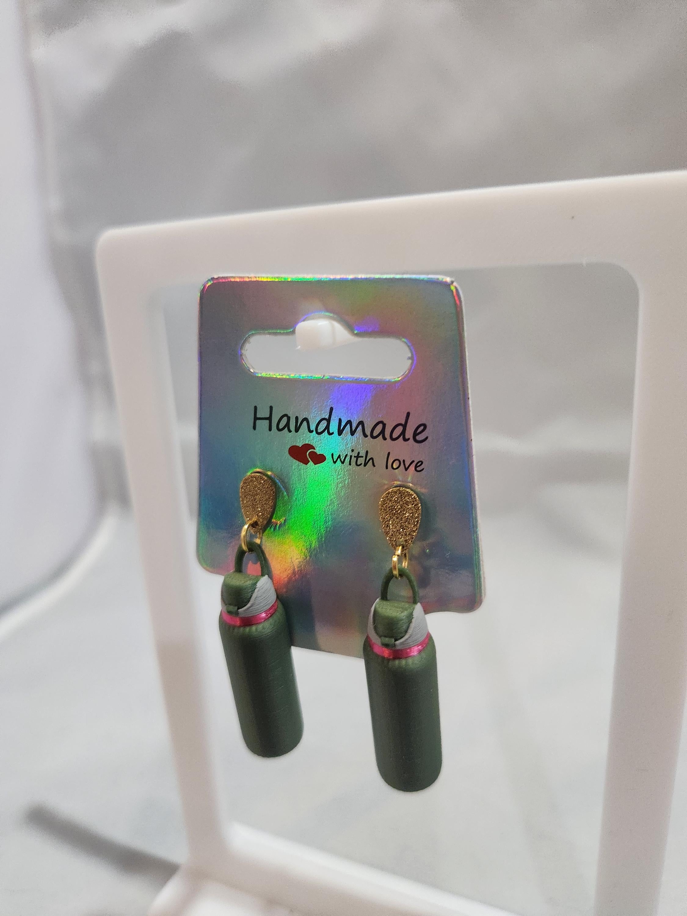 Handmade 3D printed green bottle-shaped earrings on iridescent card display