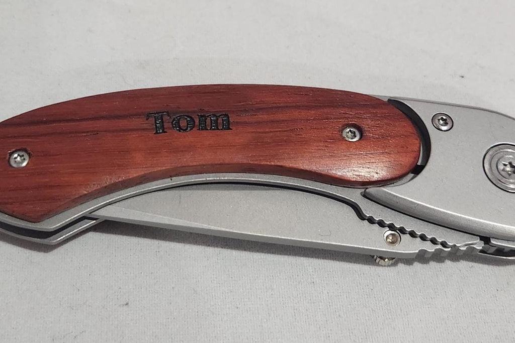 Personalized folding pocket knife with engraved wooden handle on white background