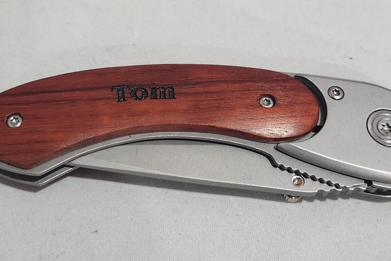 Personalized folding pocket knife with engraved wooden handle on white background